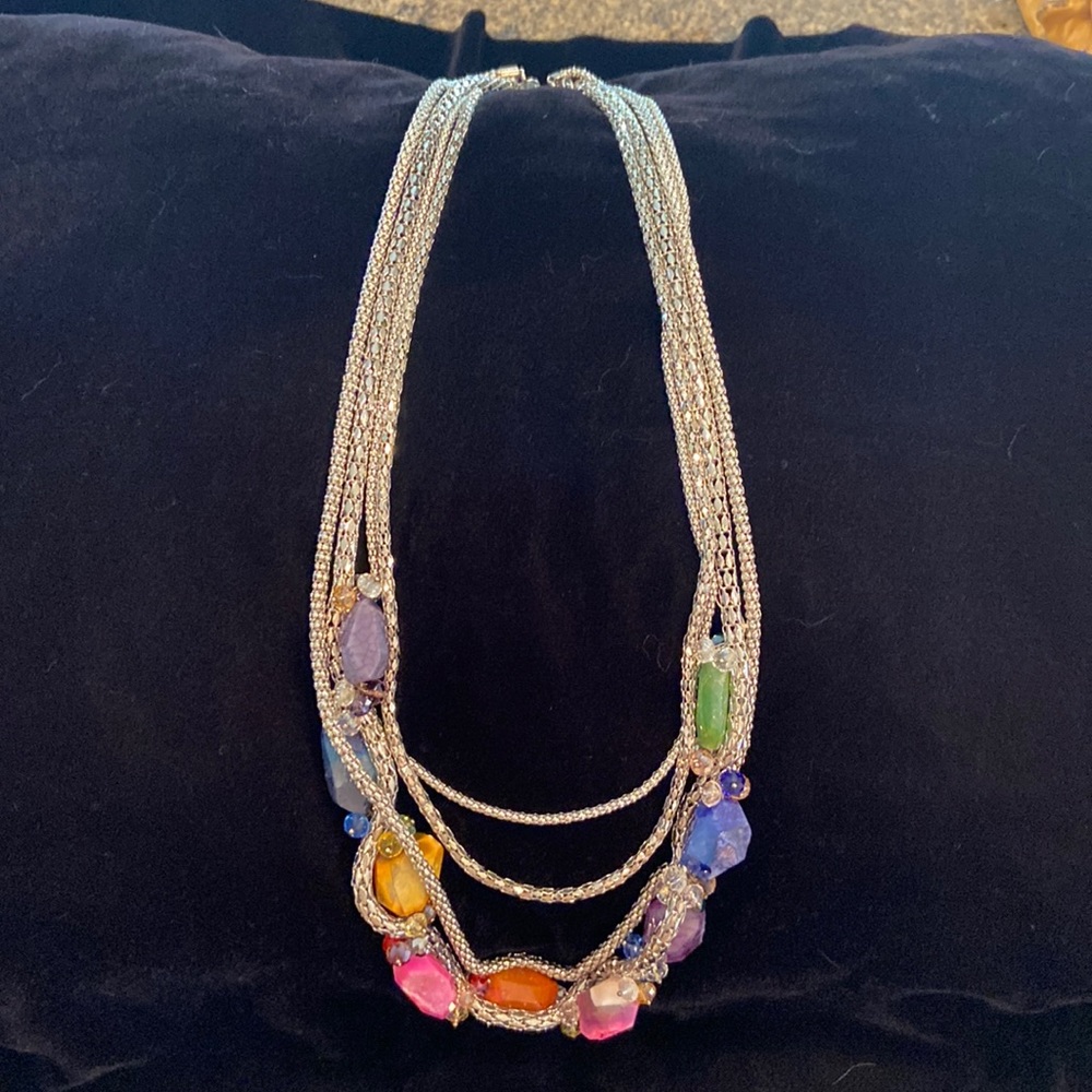 Multi layered silver colored necklace with colored stones and embellishments.